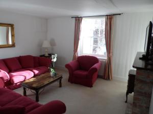 a living room with red couches and a table and a window at Stunning 3 bedroom 3 bath self catering cottage nr Stonehenge, Longleat, Avebury and Bath in Pewsey