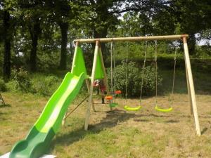 a playground with green swings in a park at Caravan du Loch in Gaël