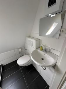 a white bathroom with a toilet and a sink at Zentral gelegenes Apartment am Bunter Garten MG09 in Mönchengladbach