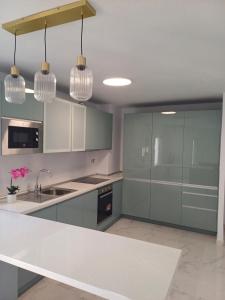 a kitchen with gray cabinets and a white counter top at Beautiful Beachfront Newly Renovated 2 Bedroom Apartment with Swimming Pool and Garden in San Luis de Sabinillas