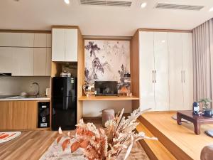 a kitchen with white cabinets and a black refrigerator at Onsen Landmark Ecopark in Cong Luận