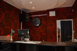 a desk with a computer and a clock on a red wall at Kungsbacken Hotell & Konferens in Katrineholm