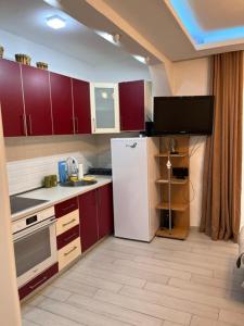 a kitchen with red cabinets and a white refrigerator at ID apartments in Tivat