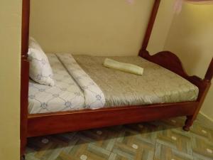 a bed with a wooden frame with a yellow pillow on it at Wana Guest House in Rubirizi