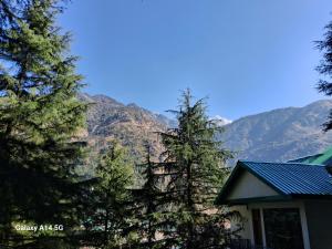 a house with trees in front of a mountain at Himalayan Triund Hill View Hostel in Dharamshala