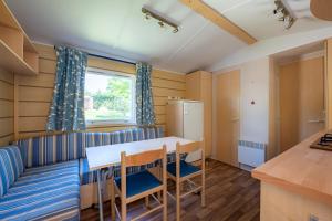 a kitchen and dining room with a table and chairs at Mobil Home classik 4-6 personnes, nature, piscine parc du pilat in Saint-Appolinard