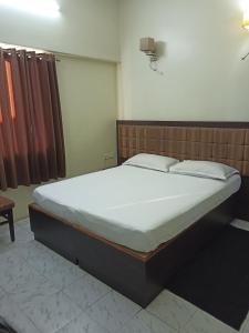 a bedroom with a large bed with white sheets at Hotel Alka in Varanasi