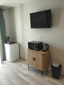 a living room with a tv on the wall and a table at Entre canal et garrigue in Roubia +17 photos