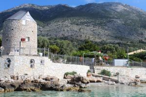 a stone tower in the water with mountains in the background at GT Traditional Windmill in Kálamos