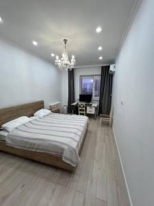 a bedroom with a bed and a desk and a chandelier at Excellent 2-room apartment near the city embankment in Astana