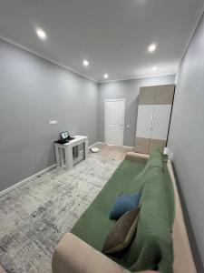 a bedroom with a green couch and a table at Excellent 2-room apartment near the city embankment in Astana