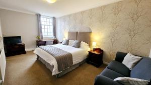 a bedroom with a bed and a couch and a television at Stoke Lodge Hotel in Stoke Fleming