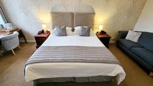 a bedroom with a large bed and a blue couch at Stoke Lodge Hotel in Stoke Fleming