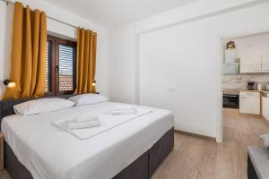 a bedroom with a large white bed with yellow curtains at APARTMENTS JADRANKa in Omišalj