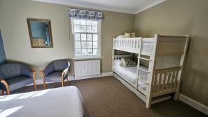 a bedroom with a bunk bed and two chairs at Stoke Lodge Hotel in Stoke Fleming