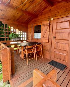 a wooden cabin with a table and chairs on a deck at Domki u Haliny in Przewłoka