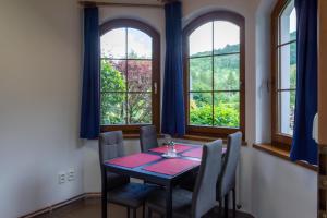 a dining room with a table and chairs and windows at Apartmány U Pivoněk in Bělá pod Pradědem