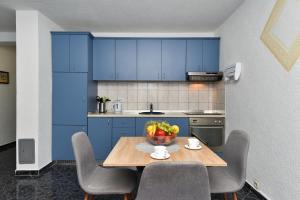 a kitchen with blue cabinets and a table with a bowl of fruit at Kaurinovic in Zaton