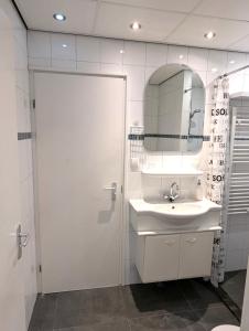 a white bathroom with a sink and a mirror at Bungalowpark De Toekomst in Ouddorp +26 photos