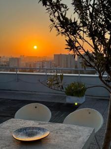 a table and chairs on a balcony with the sunset at Duplex rooftop vue Tour Eiffel in Bagnolet