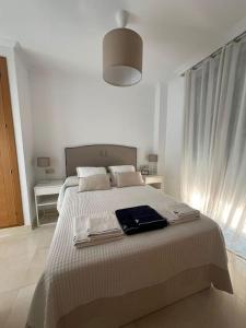 Un dormitorio blanco con una cama grande con toallas. en RE Vacacional, en Punta Umbría