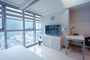 マニラにあるUptown BGC Luxury 1br Suite with Fast Wifiの白いベッドルーム(デスク、テレビ付)