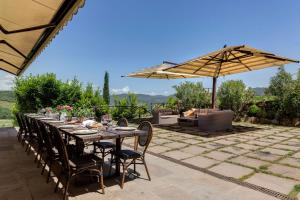 stół z krzesłami i parasol na patio w obiekcie AMORE RENTALS - Villa Mia w mieście Panzano in Chianti