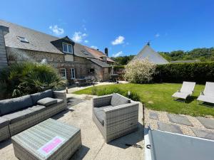 a patio with a couch and chairs in a yard at Gîte Les Eaux du Moulin piscine chauffée et jacuzzi in Vittefleur