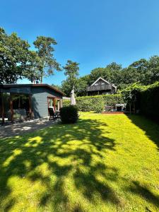 un cortile con una casa e un prato di Dubbele chalet op recreatiepark Topparken op de Veluwe in Beekbergen met grote vrije tuin en eigen parkeerplaats a Beekbergen