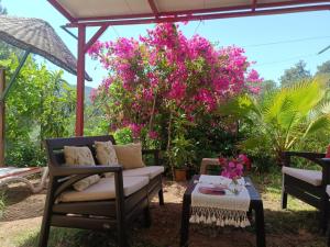 a patio with a couch and a table and pink flowers at Çirali Sunny House in Kemer