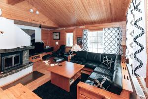 a living room with a black leather couch and a fireplace at Villa Polaris in Äkäslompolo