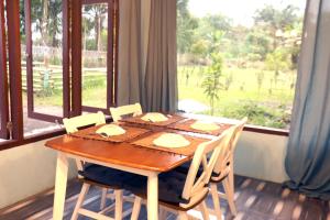 a dining room table with chairs and a large window at Villa Lokon Tomohon in Tomohon