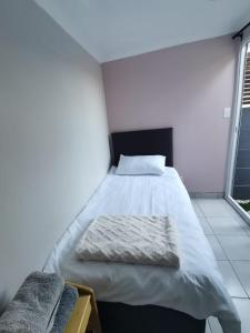 een groot bed in een kamer met 2 ramen bij Cozy Business overnighter in Bellville