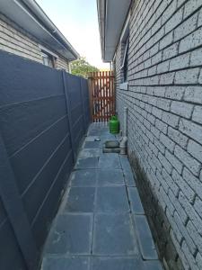 een steegje met een bakstenen muur en een groene emmer bij Cozy Business overnighter in Bellville