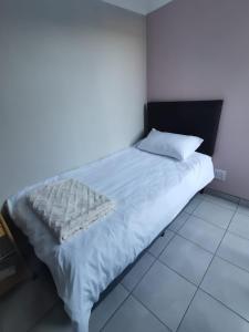 een slaapkamer met een wit bed met een zwart hoofdeinde bij Cozy Business overnighter in Bellville