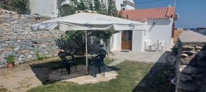 a table and chairs under an umbrella in a yard at Amalia beach apartment in Kokkari
