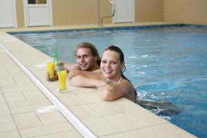 a man and a woman in a swimming pool at Hotel Malamut in Nové Hamry