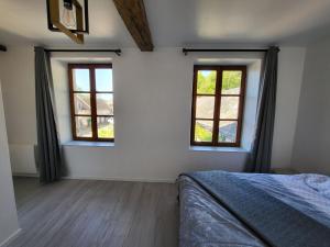 a bedroom with two windows and a bed in it at Haras de la Ressée in Agnez-lès-Duisans