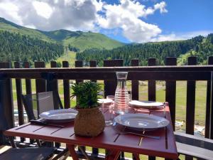 un tavolo di legno con piatti e un vaso su un balcone di Charmant Studio Le Lioran - Tour Sumène a Laveissière