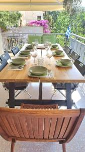 a wooden table with plates and wine glasses on a patio at quiet apartment near the sea in Athens