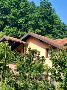 ein gelbes Haus mit Bäumen davor in der Unterkunft Apartment Panonija in Tuzla