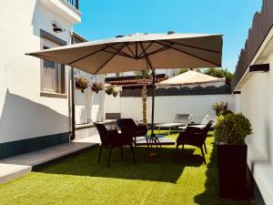 a table and chairs under an umbrella on a lawn at Kalasó Design Guest House - Rome Airport in Fiumicino