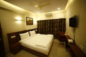 a bedroom with a bed and a desk and a television at Hotel skml Grand in Visakhapatnam