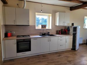 eine Küche mit weißen Schränken und einer Spüle in der Unterkunft Ferienhaus Bartelshagen 1 in Marlow