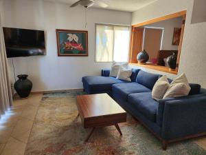 a living room with a blue couch and a coffee table at Beach Eateries Shops 10 min walk Golf view in San José del Cabo