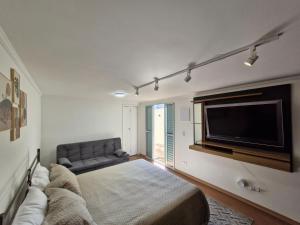 a living room with a couch and a flat screen tv at Suíte privativa em lindo casarão in Sao Paulo +13 photos
