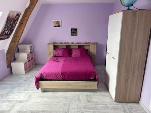 a bedroom with a bed with a purple bedspread at La forge in Auvers