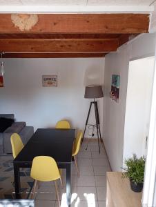 a dining room with a black table and yellow chairs at Appartement dans Villa à marignane in Marignane