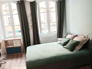 a bedroom with a bed with two windows at Studio - Centre-ville in Morlaix +8 photos