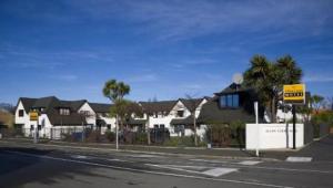 een lege straat met huizen en een bord aan de kant van de weg bij Allan Court Motel in Dunedin